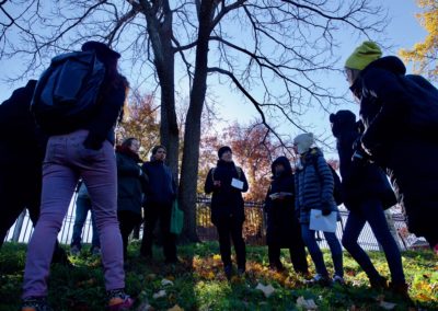 a group of people stand around a tree listening